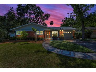 Charming brick home featuring manicured lawn, sidewalk, and meticulous landscaping creates a welcoming curb appeal at 202 S Hesperides St, Tampa, FL 33609