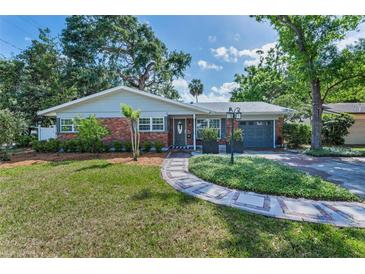Charming single-story brick home with a landscaped yard, walkway, and gray garage door at 202 S Hesperides St, Tampa, FL 33609