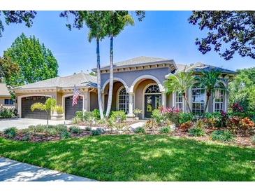 Beautifully landscaped home with a well-manicured lawn, arched entrance, and a spacious three-car garage at 3212 Sunset Lakes Blvd, Land O Lakes, FL 34638