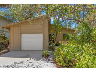 Inviting home with lush landscaping, mature trees, and a convenient attached garage at 407 Indiana Ave, Crystal Beach, FL 34681