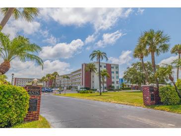 Low-angle shot of a condominium complex with tropical landscaping and mature palm trees at 5575 Gulf Blvd # 329, St Pete Beach, FL 33706