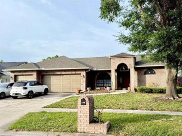 Charming brick home with a well-manicured lawn, two-car garage, and attractive landscaping at 1418 Buckner Rd, Valrico, FL 33596
