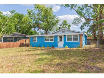 Charming blue home with stone accents, well-maintained lawn and mature trees at 1513 Escort Ave, Tampa, FL 33610