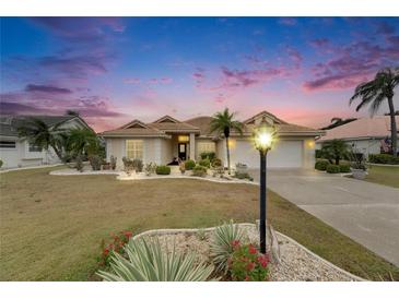 Inviting single-story home featuring a tile roof, two-car garage, manicured lawn, and mature palm trees at 2017 S Pebble Beach Blvd, Sun City Center, FL 33573