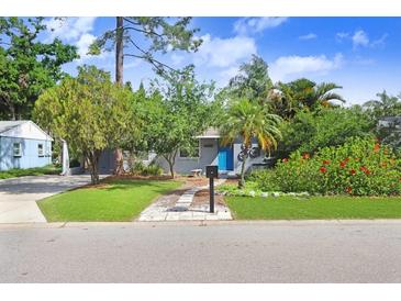 Charming home featuring a landscaped front yard, complemented by a bright blue door and vibrant green foliage at 4105 W Bay Villa Ave, Tampa, FL 33611