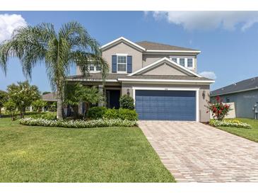 Inviting two-story home with a blue garage door, lush lawn, and well-manicured landscaping, creating great curb appeal at 879 De Soto Blvd, Tarpon Springs, FL 34689