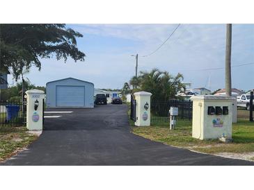 Property entrance featuring a long driveway, steel building, black iron fence and decorative entrance posts at 3302 W Shell Point Rd, Ruskin, FL 33570
