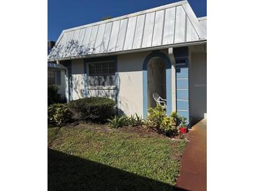 Charming home exterior with a metal roof, blue trim and an open, arched porch entrance at 4217 Tamargo Dr # A, New Port Richey, FL 34652