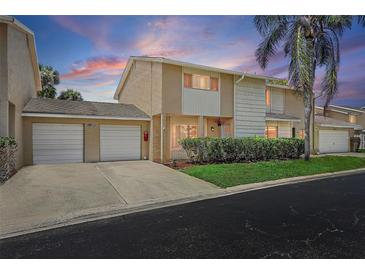 Charming townhouse featuring a two-car garage, well-maintained landscaping, and inviting curb appeal under a beautiful sunset sky at 6490 Cape Hatteras Ne Way # 4, St Petersburg, FL 33702