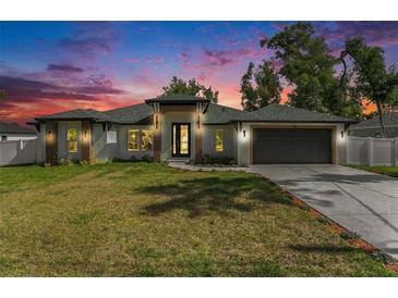 Charming single-story home with a well-manicured lawn and welcoming entrance with black double doors at sunset at 106 Ne 1St Ave, Lutz, FL 33549