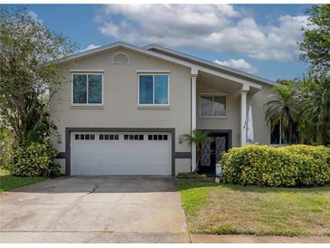 Charming two-story home featuring a two-car garage, manicured landscaping, and decorative front door at 1326 Moss Dr, Dunedin, FL 34698