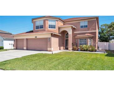 Charming two-story home with landscaped yard, a three-car garage, and a well-maintained lawn at 1751 Split Fork Dr, Oldsmar, FL 34677