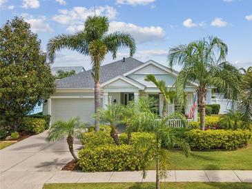 Charming single-story home featuring a manicured lawn, lush tropical landscaping, and a welcoming front porch at 525 Manns Harbor Dr, Apollo Beach, FL 33572