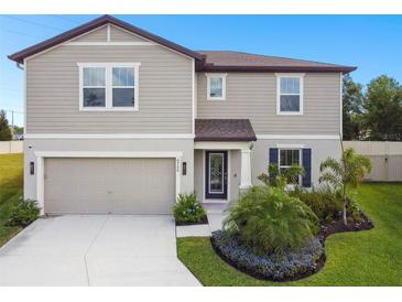 Charming two-story home with a well-manicured lawn, attached garage, and lovely landscaping at 6700 Devlin Ln, Wesley Chapel, FL 33545