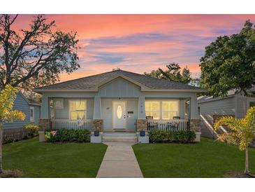 Charming single-story home featuring a cozy front porch and beautifully landscaped lawn at sunset at 1410 25Th N St, St Petersburg, FL 33713
