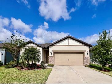 Charming single-story home features a well-manicured lawn and a neutral colored facade with stone accents at 6293 Bradford Woods Dr, Zephyrhills, FL 33542