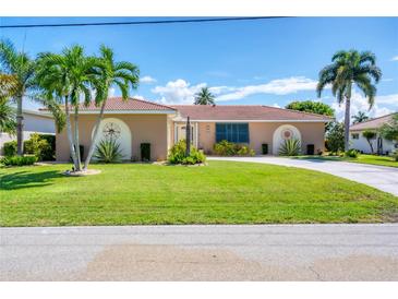 Charming single-story home with well-manicured lawn, circular driveway, and tasteful landscaping, including palm trees at 890 Coronado Dr, Punta Gorda, FL 33950