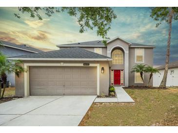 Two story home featuring an attached two car garage, manicured lawn and a bright red front door at 10308 Boyette Creek Blvd, Riverview, FL 33569