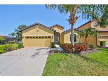Charming single-story home with yellow facade, well-manicured lawn, and a two-car garage at 336 Silver Falls Dr, Apollo Beach, FL 33572