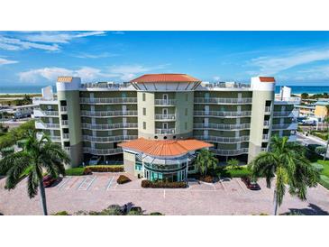 Beautiful multi-story condo building near the beach with a circular driveway, lush landscaping, and ample parking at 11605 Gulf Blvd # 203, Treasure Island, FL 33706