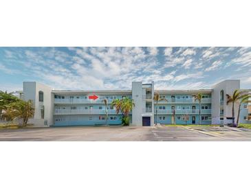 Exterior of a light blue condo building featuring balconies and palm trees in a sunny neighborhood at 12405 3Rd E St # 306, Treasure Island, FL 33706