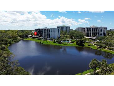 Scenic view of the condominium complex and its community pool, set by a serene lake at 220 Belleview Blvd # 104, Belleair, FL 33756