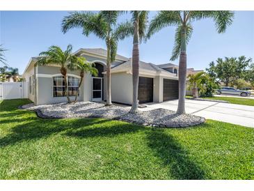 Charming single-story home featuring a well-manicured lawn, palm trees and a three car garage at 511 York Dale Dr, Ruskin, FL 33570
