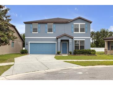 Charming two-story home boasts a well-manicured lawn, beautiful blue shutters and a matching two car garage door at 662 Petal Mist Ln, Brooksville, FL 34604