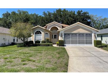 Inviting single-story home with a well-manicured lawn, screened garage, and charming curb appeal at 11185 Heathrow Ave, Spring Hill, FL 34609