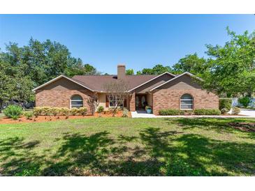Charming brick home featuring a well-manicured lawn, complemented by mature trees and lush landscaping at 12408 Wexford Hills Rd, Riverview, FL 33569