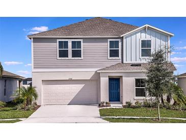 Two-story home featuring a blue door, two car garage, light grey lap siding and manicured front lawn at 13034 Wellspring Dr, Lithia, FL 33547