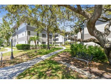 Beautiful condo exterior with a walkway, mature trees, and lush landscaping offering a tranquil setting at 2650 Countryside Blvd # B-110, Clearwater, FL 33761