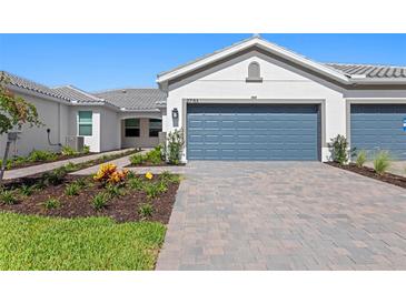 Beautiful single-story home featuring a blue garage door, tile roof, and landscaped front yard at 27153 Capri Shores Cir, Englewood, FL 34223