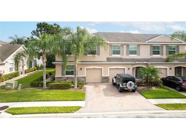 Inviting townhome featuring a paver driveway, attached garages, and manicured landscaping at 3844 Silverlake Way, Wesley Chapel, FL 33544