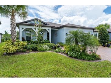 Charming home featuring lush landscaping, a well-manicured lawn, and a welcoming covered entryway at 5597 Bay Tide Ct, Land O Lakes, FL 34638