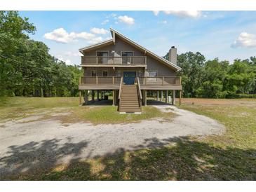 Inviting two-story home with wraparound porch, set on stilts, blending architectural design and outdoor living at 7606 Four Pines Rd, Plant City, FL 33565