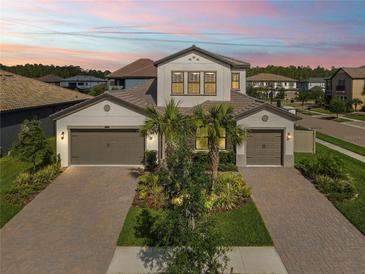 Beautiful two-story home featuring a three car garage, a brick paved driveway, and lush landscaping at 4365 Frontera Ln, Wesley Chapel, FL 33543