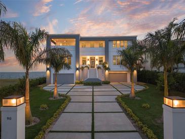 Stunning two-story home with manicured lawn, driveway, and palm trees, set against a picturesque sunset backdrop at 90 Martinique Ave, Tampa, FL 33606