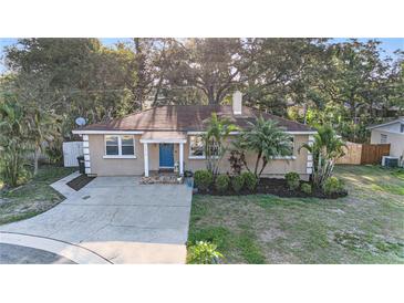 Charming home with a well-manicured lawn, mature trees, and a blue front door at 1513 Owen Dr, Clearwater, FL 33759