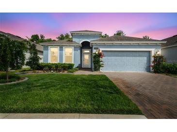 Charming one-story home with a well-maintained lawn, red brick driveway and pleasing blue exterior paint at 19629 Fort King Run, Brooksville, FL 34601