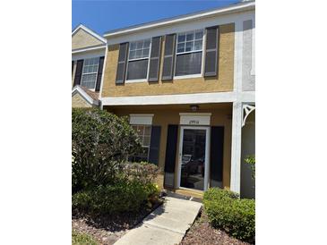Two-story home featuring an inviting front entrance, dark shutters, and a well-maintained lawn with garden at 29931 Playa Del Rey Ln, Wesley Chapel, FL 33543