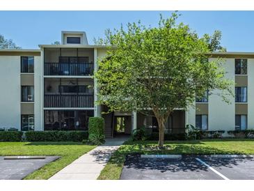Low-rise condominium building with well-maintained landscaping, parking, and walkway to the entrance at 3166 Lake Pine S Way # E3, Tarpon Springs, FL 34688