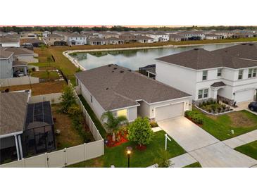 An aerial view shows this beautiful home with a screened-in pool, fenced yard and a picturesque pond in the neighborhood at 33581 Elm Hill Br, Wesley Chapel, FL 33545