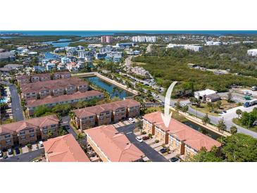 An aerial view of a condo complex with a pond, lush greenery and beautiful views of the ocean in the distance at 5033 Blue Runner Ct, New Port Richey, FL 34652