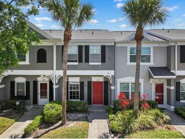 Charming townhome featuring a red door, lush landscaping, and beautiful palm trees at 273 Countryside Key Blvd, Oldsmar, FL 34677