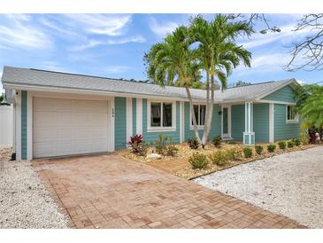 Charming home featuring a brick driveway, a one car garage and meticulous landscaping with tropical plants at 504 69Th St, Holmes Beach, FL 34217