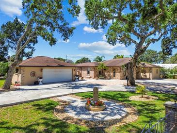 Lovely single-story home with a circle driveway and fountain on a manicured lawn beneath mature shade trees at 6732 Udell Ln, Hudson, FL 34667