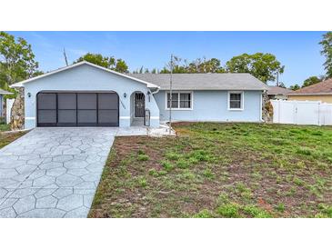 Charming light blue single Gathering home featuring an attached garage and landscaped front yard at 12083 Rockford St, Spring Hill, FL 34608