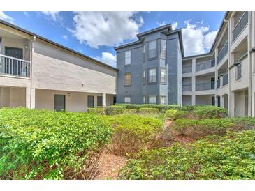 A multi-story condo with mature landscaping, featuring a cool gray exterior and multiple balcony levels at 13210 Arbor Isle Dr # 207, Temple Terrace, FL 33637