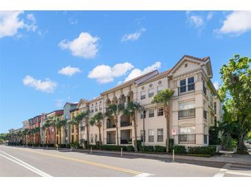 Exterior view of a multi-story condo building with palm trees lining the street at 2410 W Azeele St # 228, Tampa, FL 33609